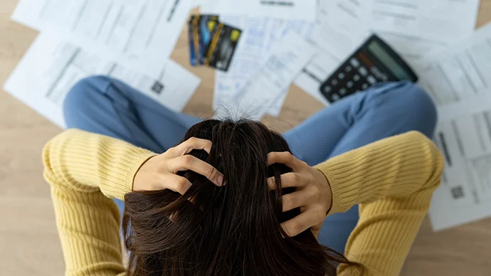 Financial Warning Signs You Can't Ignore Woman stressed about a lot of credit card debt and bills on the floor.