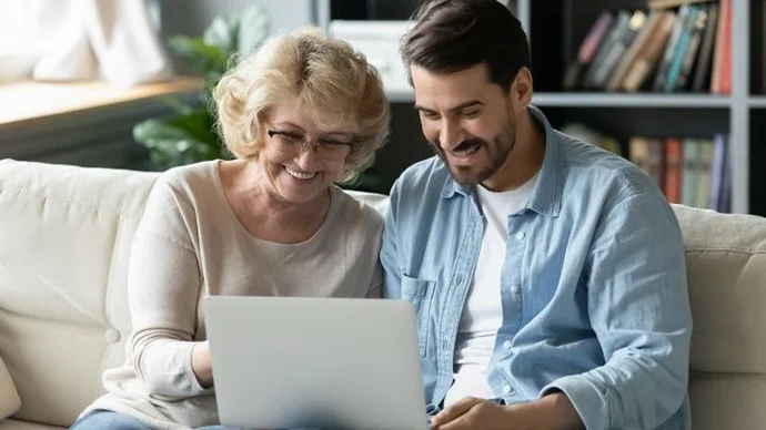 Managing Mom's Money Son looking over finances on a laptop with his mother