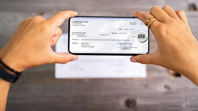 Avoid Check Deposit Scams Person taking a picture of a check for deposit